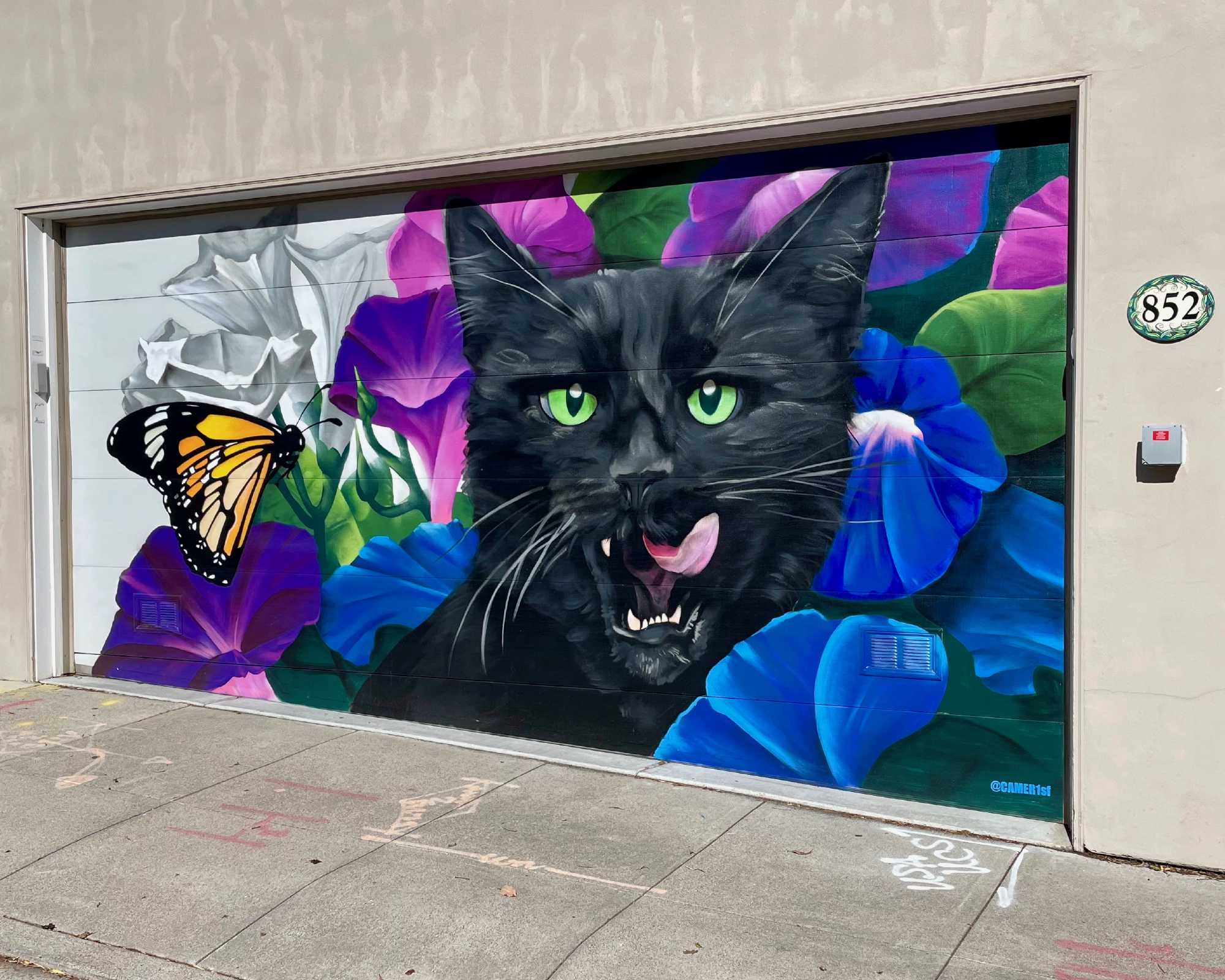 Mural of a cat licking its chops on a garage door